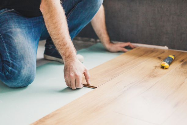 a man's hands laying flooring
